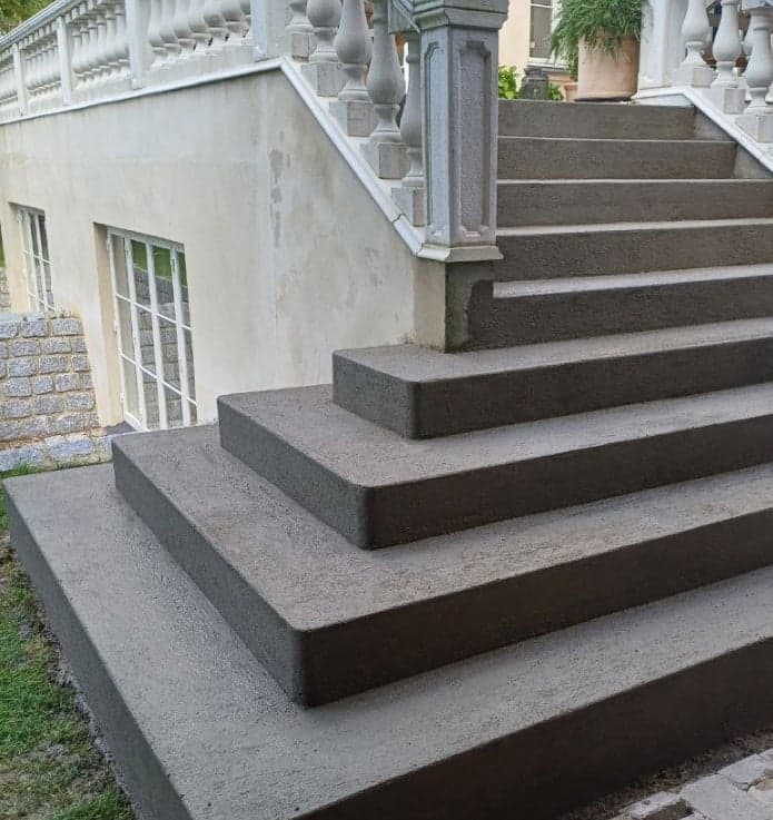 Nybelagte betontrin foran bolig med hvid balustrade